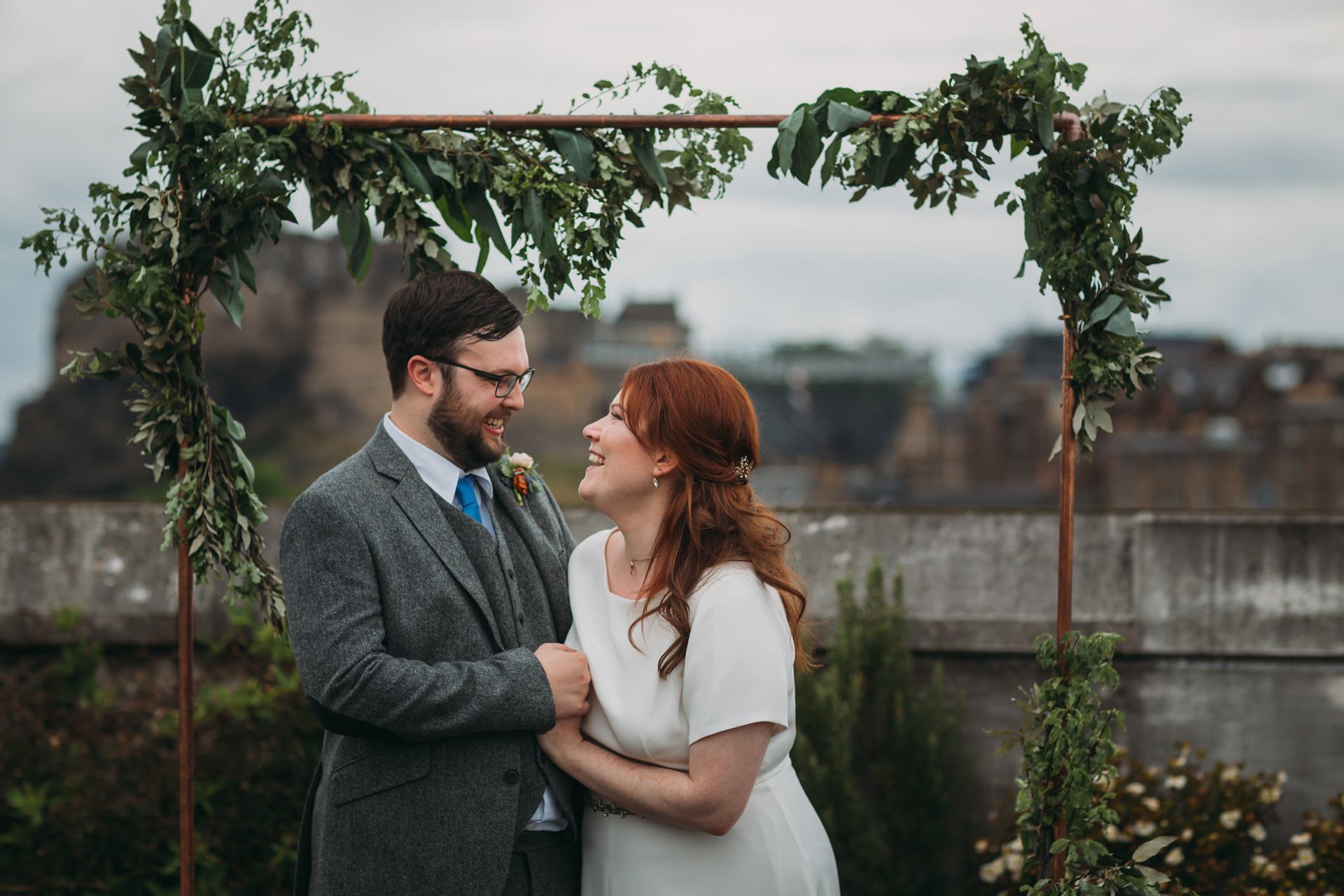 eloping to scotland romantic elopement photography Scotland couple laugh under floral archway in Edinburgh