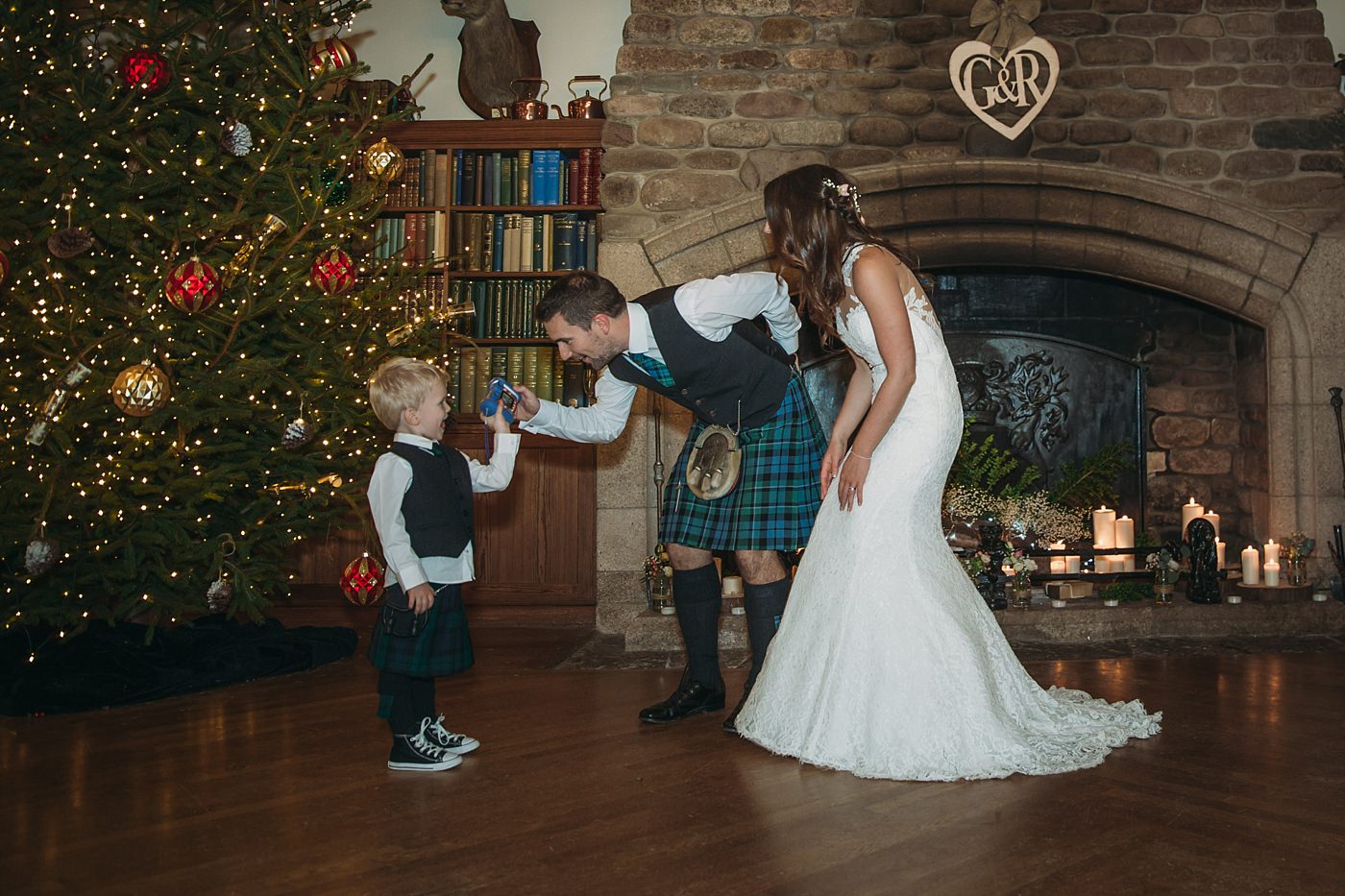 bride and groom play with nephew at their Christmas wedding at Glen Tanar