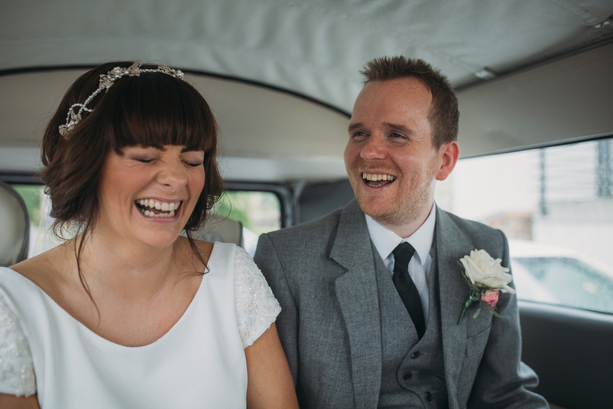 best wedding photographs of a coupe laughing at 3 sisters bake