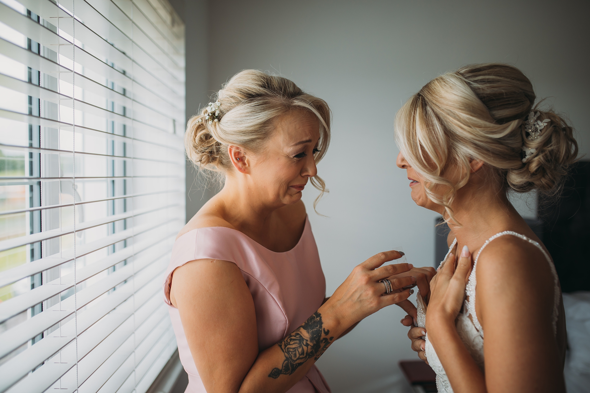 best wedding photographs of a bride and her bridesmaid crying together with happiness