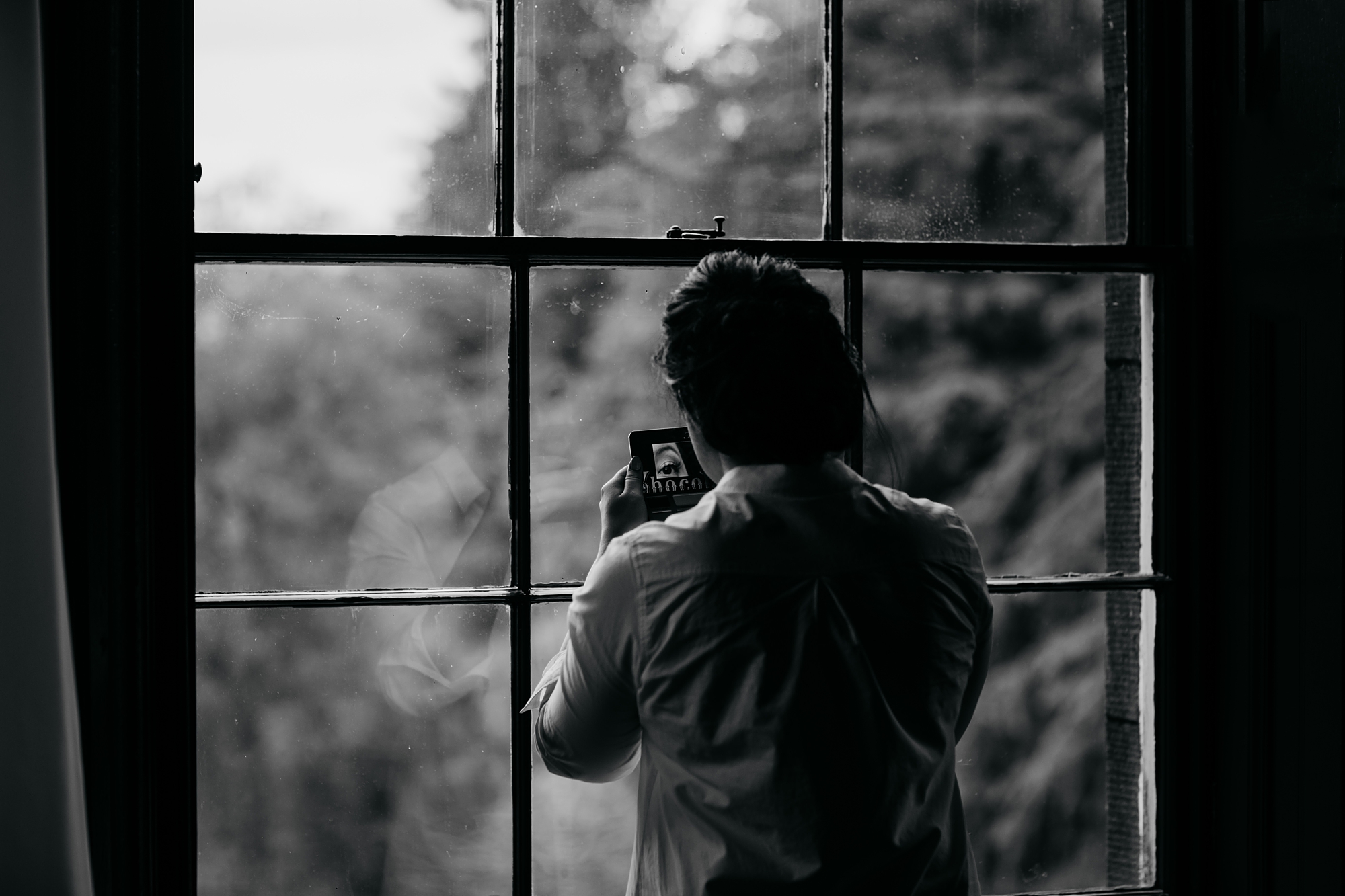 A bride doing her makeup, her eye reflected in her small mirror best wedding photographs