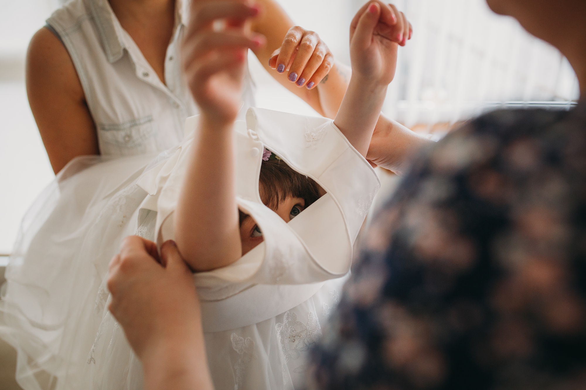 best wedding photographs i renfrewshire, flower girl peeks out as her dress is put on