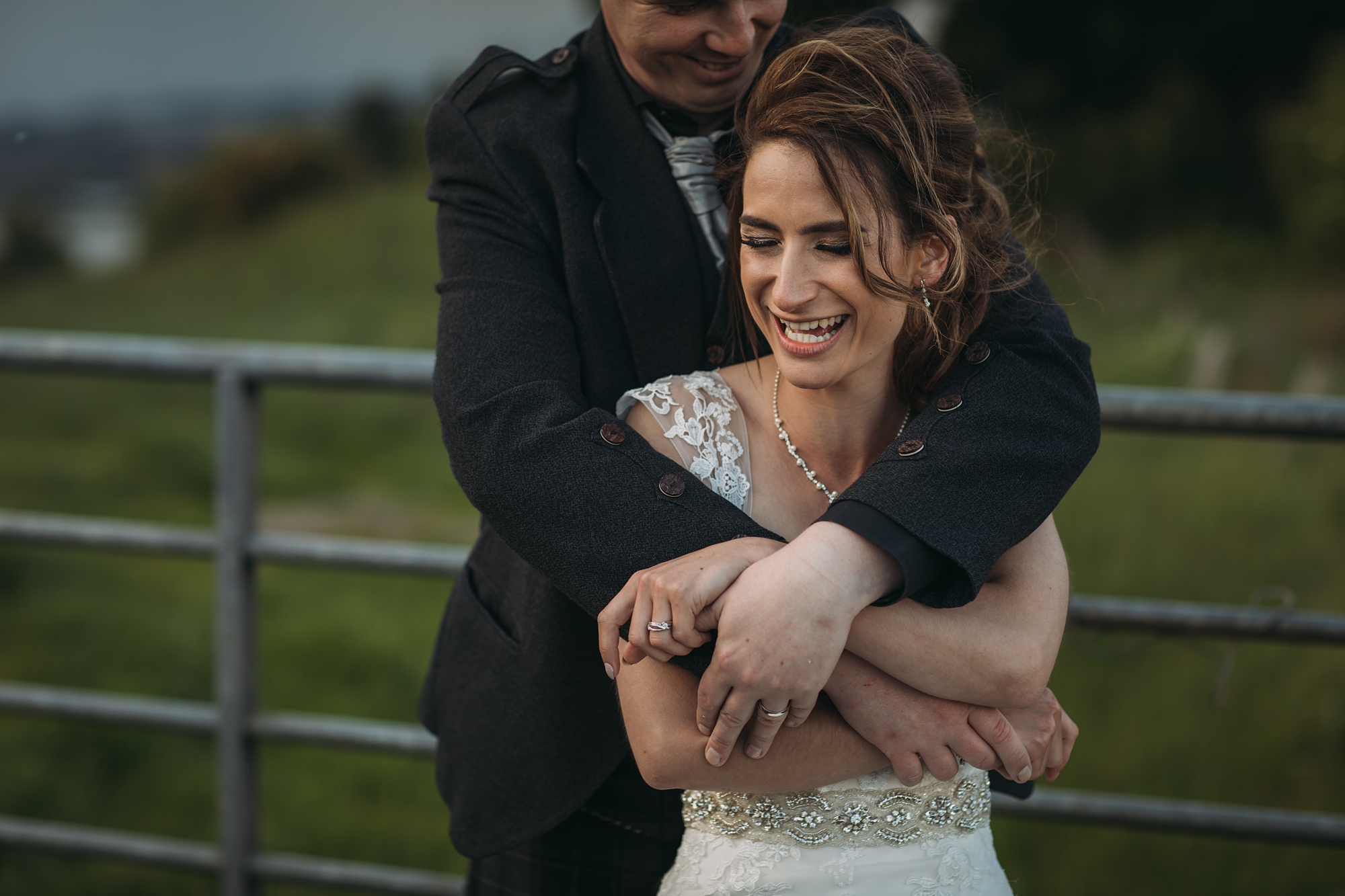 A bride laughs as she is hugged by her tall husband - best wedding photographs