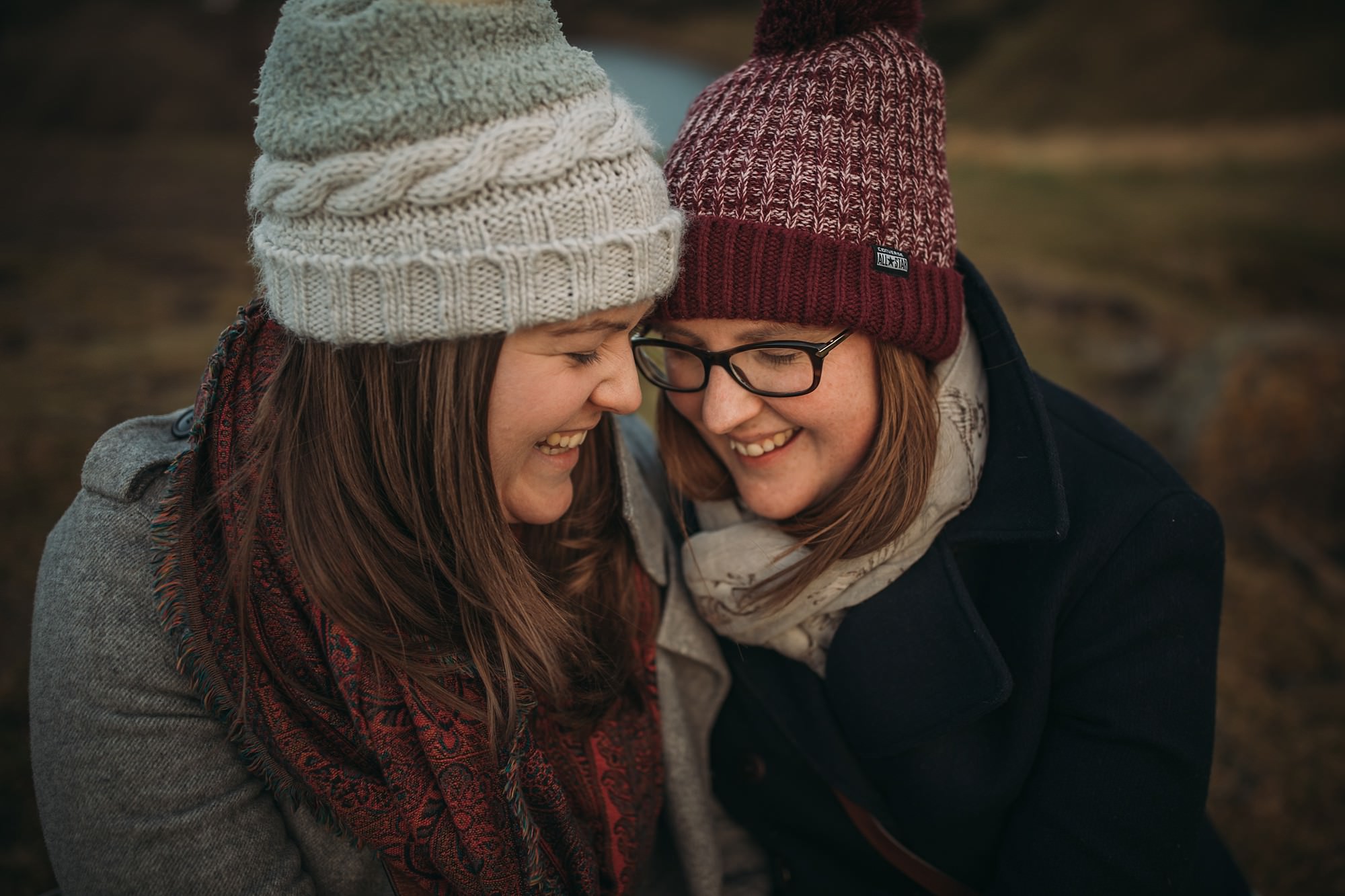 two women cuddle together during winter engagement shoot, used in our tips blog