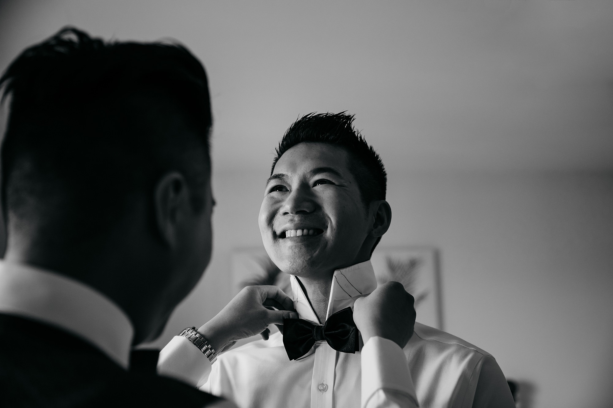 Groom helps his hudband to be with his bowtie ahead of their Glasgow elopement.