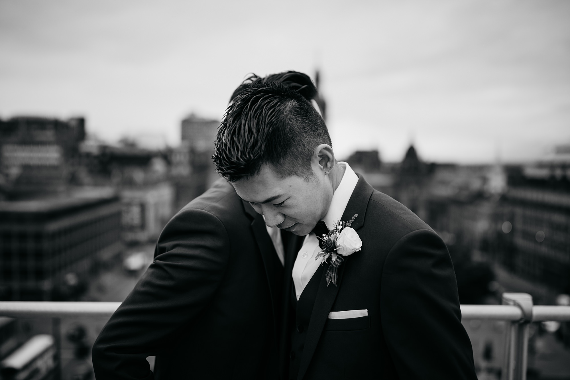 Two grooms embrace on a rooftop overlooking the city during their Glasgow elopement.