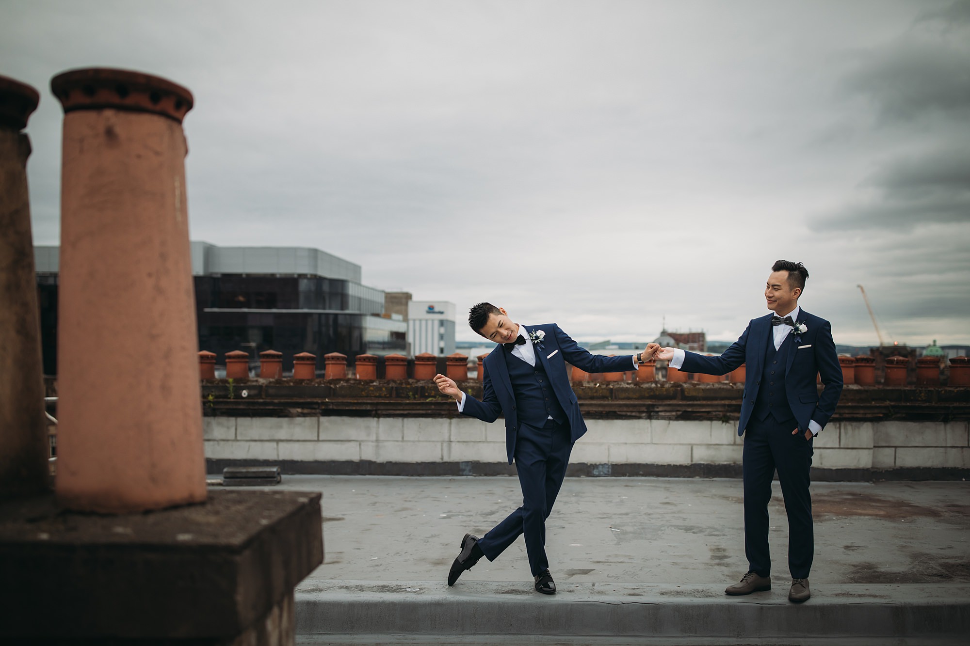 Two grooms dance together on a rooftop during their Glasgow elopement.