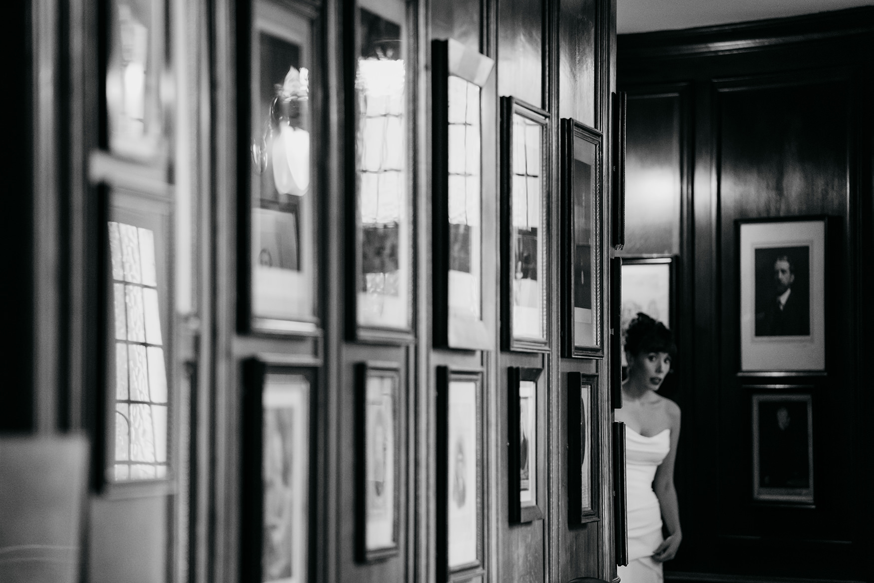 black and white image of nervous looking bride peeking round corner at her Royal College of Physicians Wedding ceremony