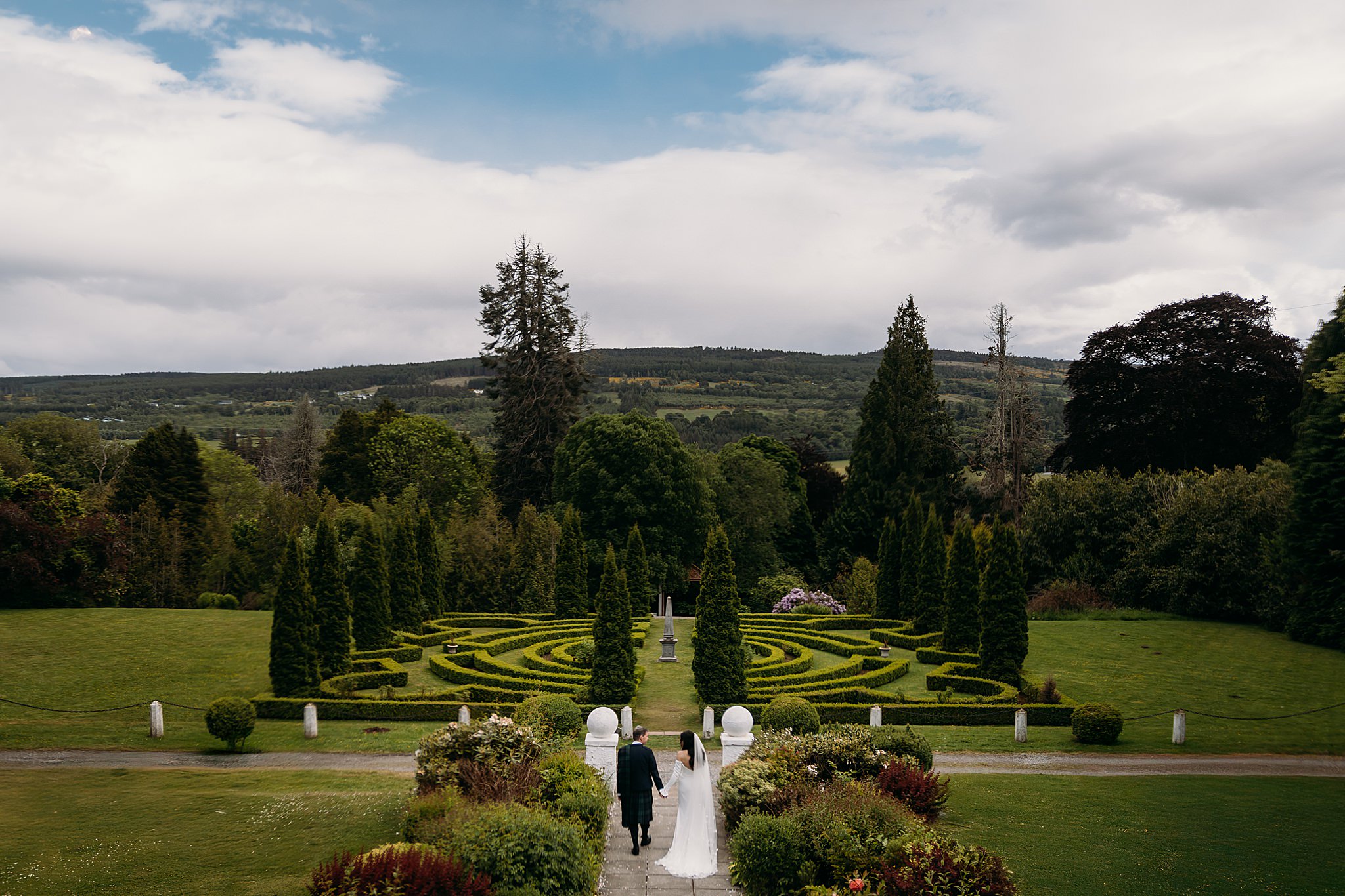 Newlyweds walk through gardens during their two day Indo-Scottish Achnagairn Castle wedding