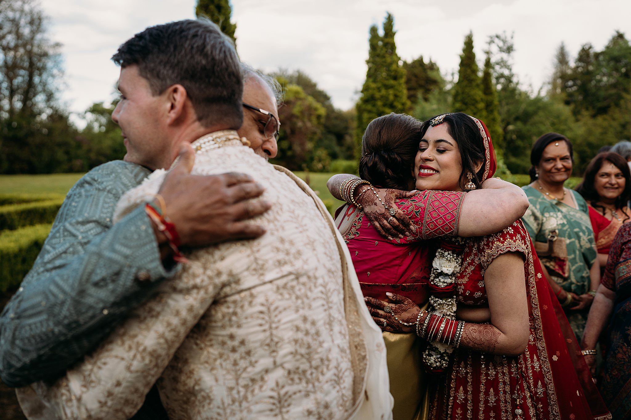 Brides dad hugs groom and brides mum hugs bride at Indo-Scottish Achnagairn Castle wedding