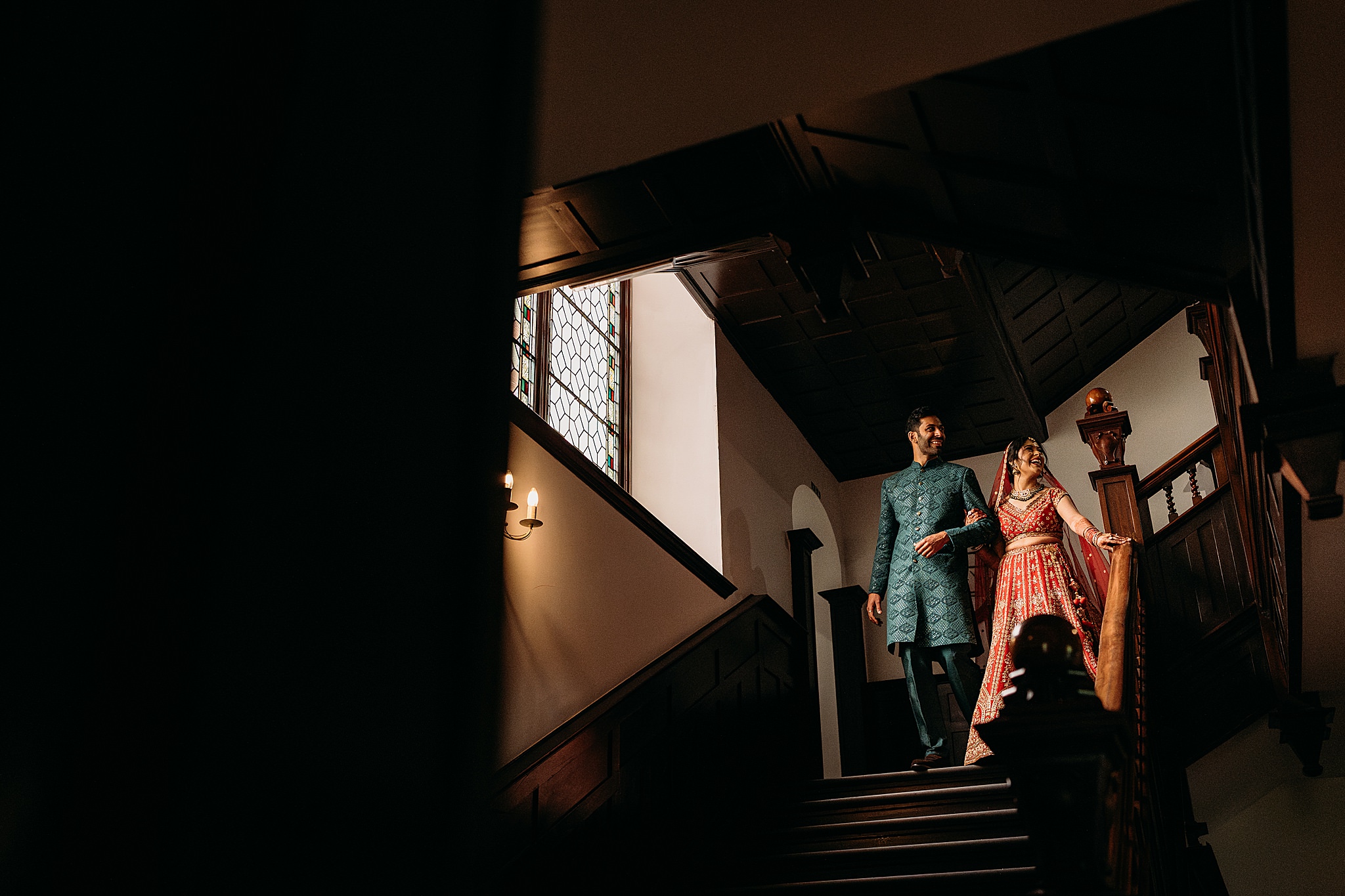 Bride waits at top of stairs with her brother before her Indo-Scottish Achnagairn Castle wedding