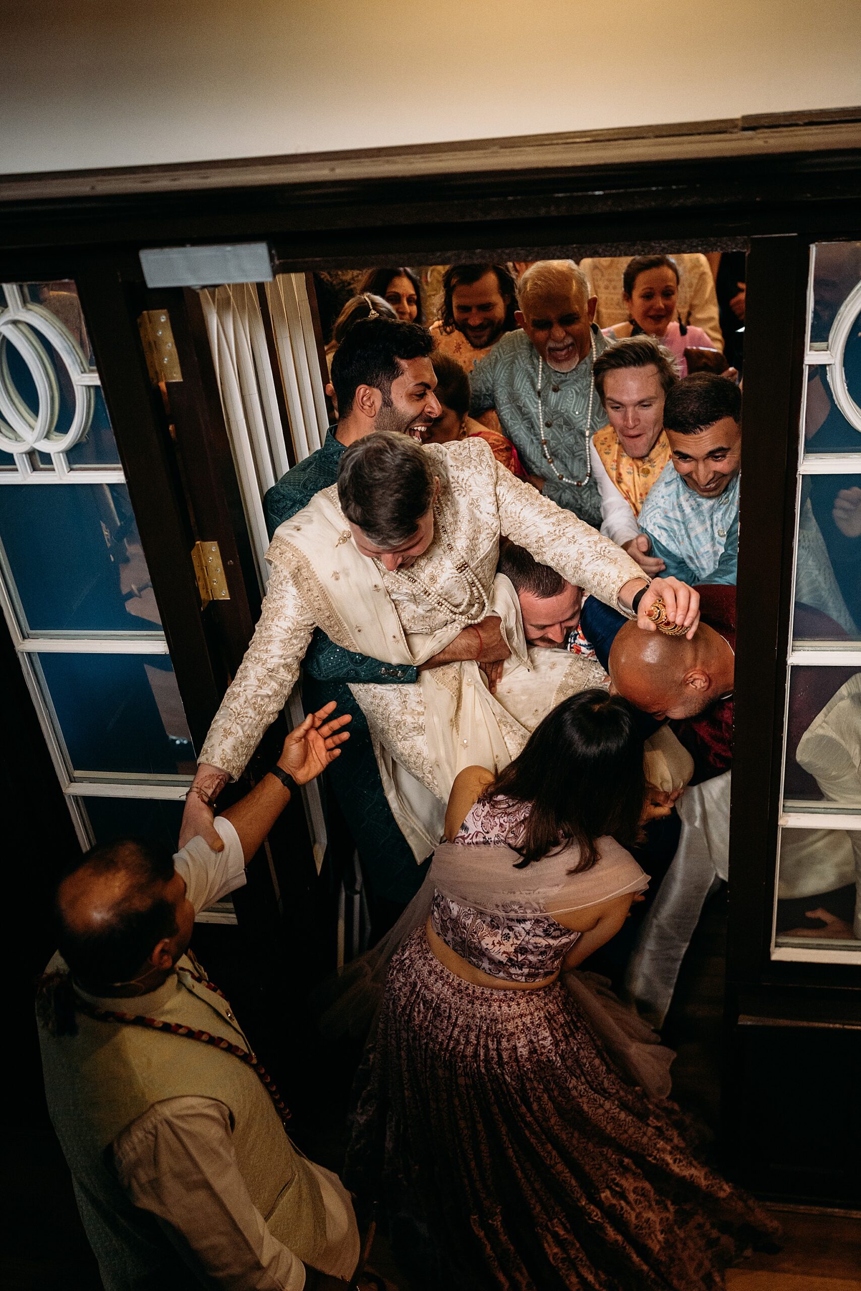 Groom is wrestled for his shoes at an Indo-Scottish Achnagairn Castle wedding