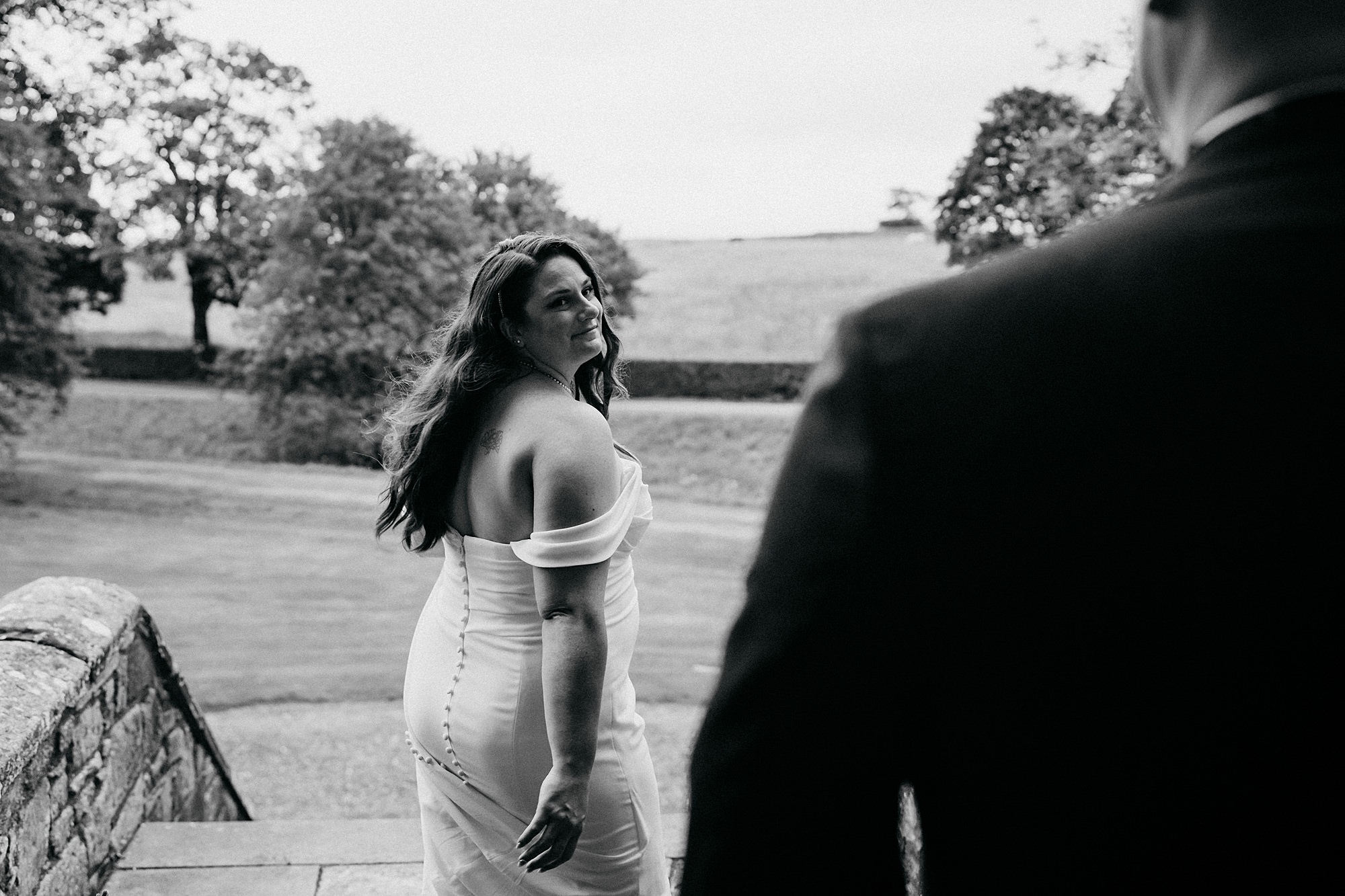 Black and white image of a bride looking back at her husband. Relaxed wedding photography at Rowallan Castle.