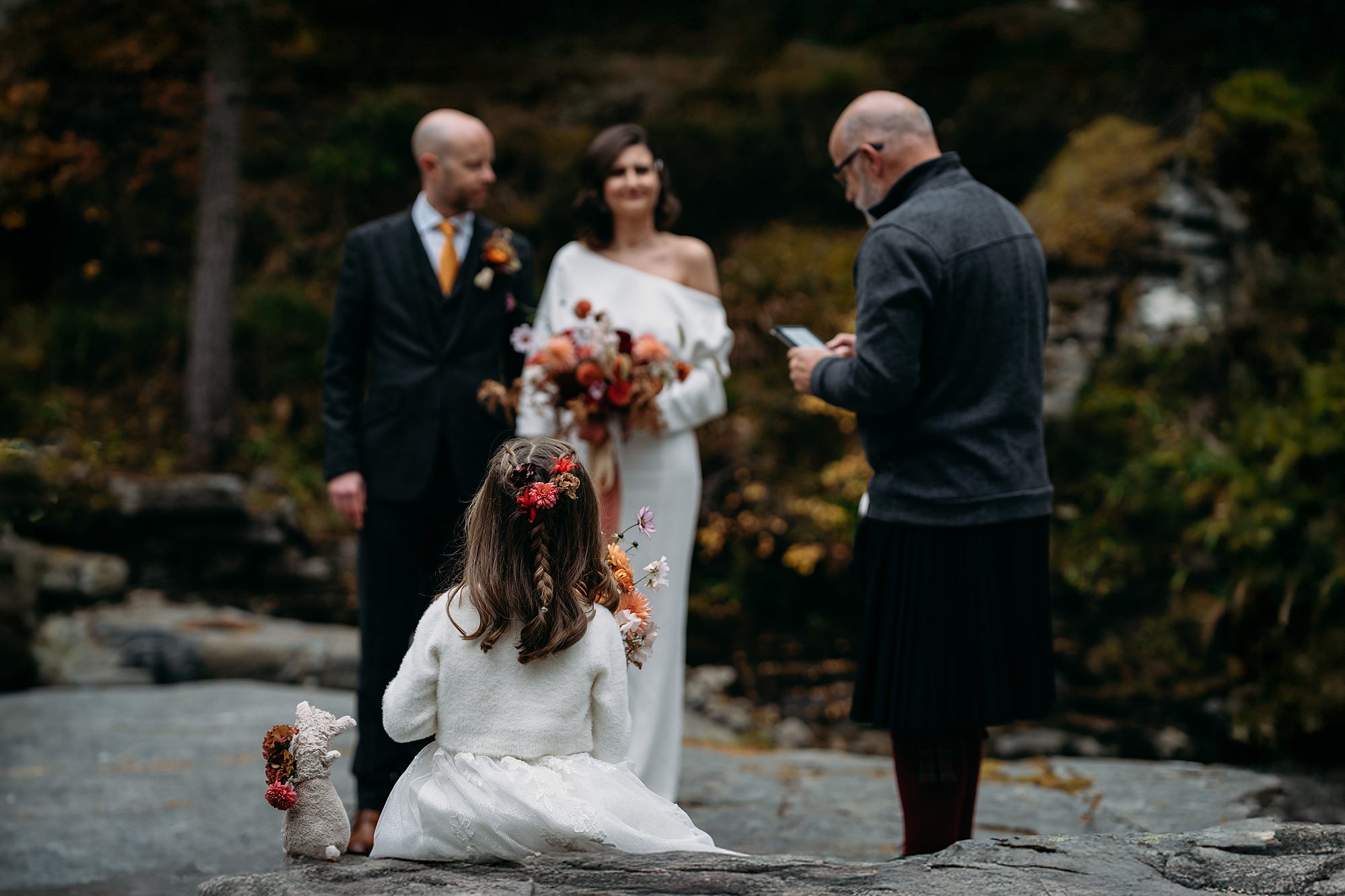 A little girl and her teddy watches her mum and dad get married at the Devils Punchbowl. Relaxed wedding photography in Braemar with Coorie Wedding Planning. 