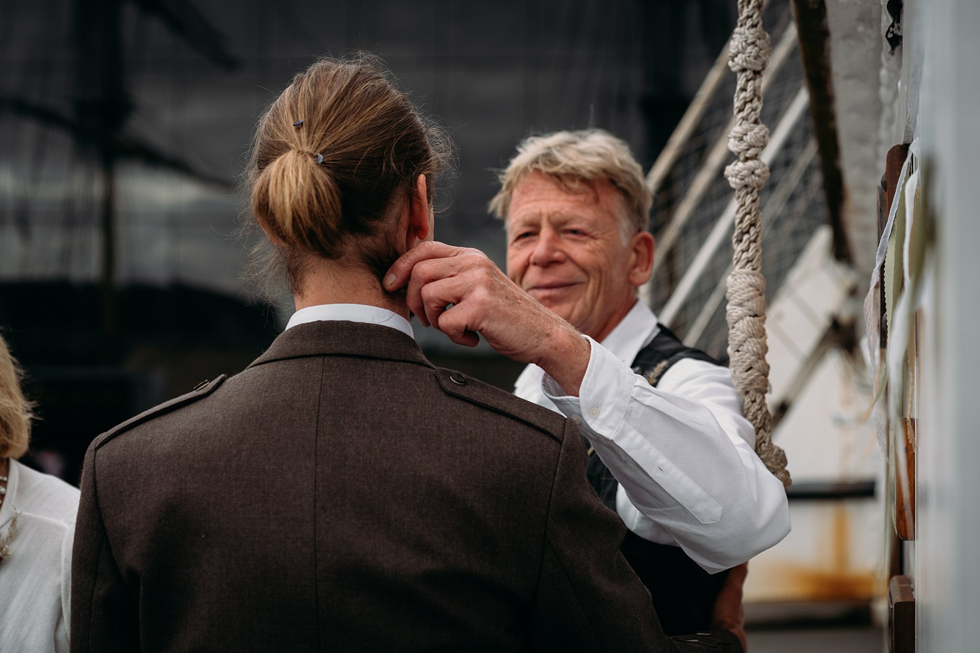 A dad touches his grown sons cheek on his wedding day. Relaxed wedding photography at the Tall Ships Glasgow.