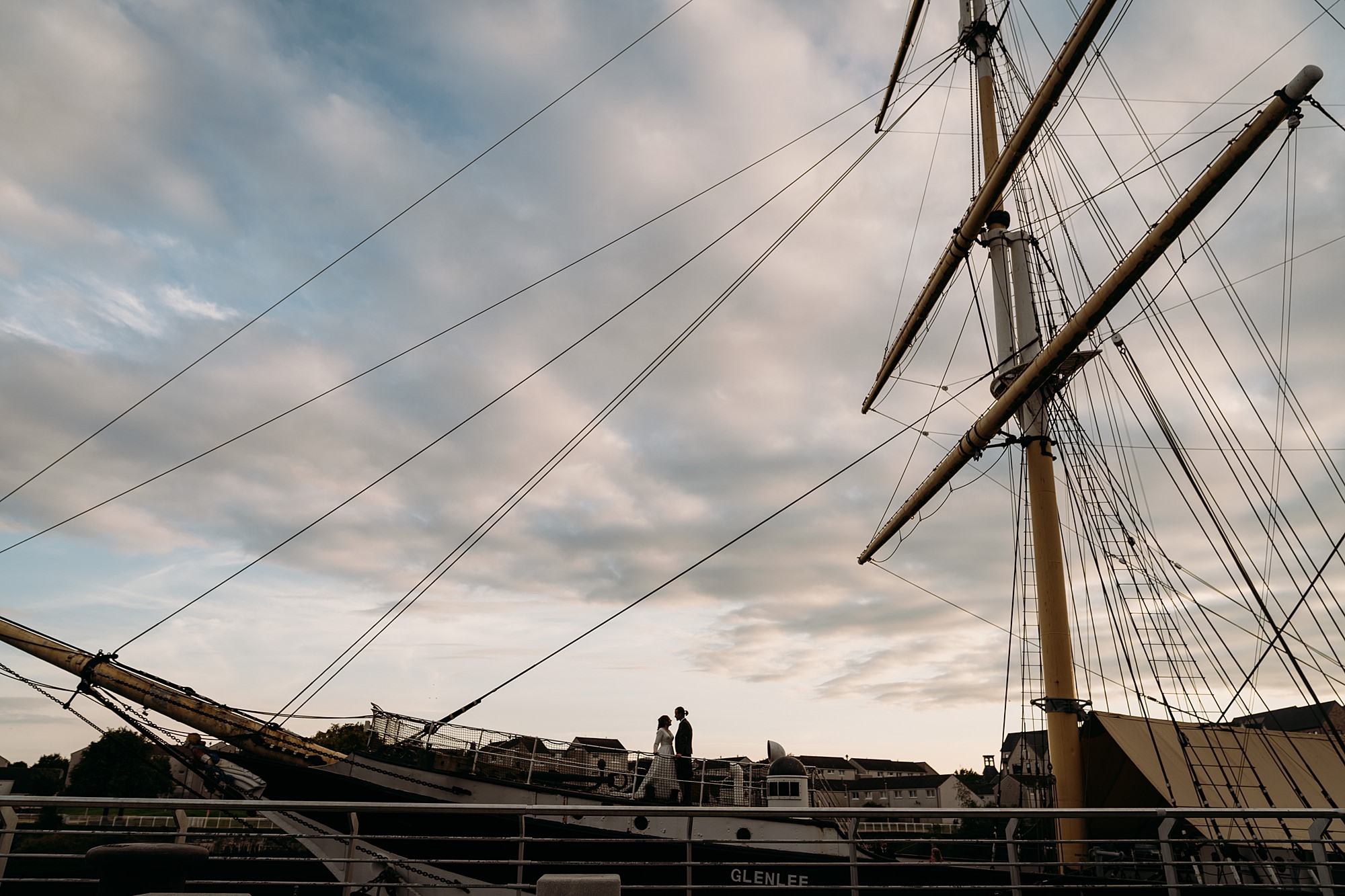 A couple embrace on the deck of The Tall Ship Glasgow. Relaxed wedding photography by Jo + Liam