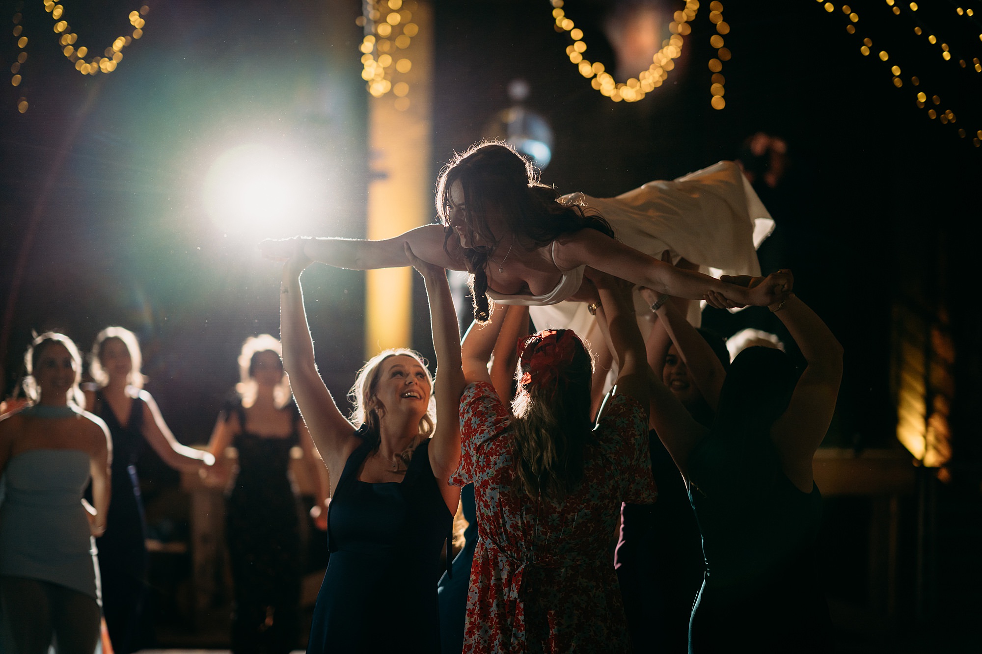 A bride is lifted by her friends dirty dancing style on the dancefloor at a Harelaw farm wedding. Relaxed wedding photography.