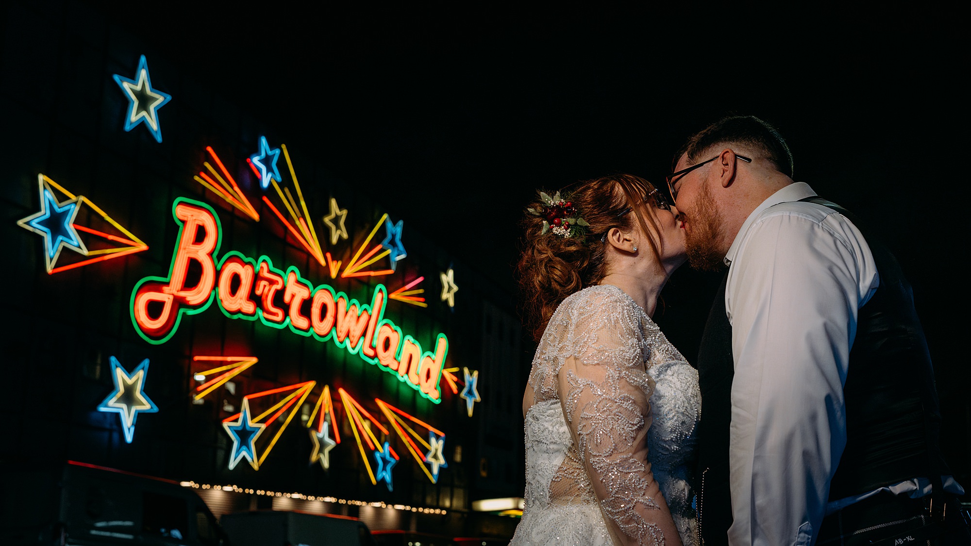 Couple kiss outside Barrowlands Ballroom. Sign is fully lit up. Relaxed Glasgow wedding photography