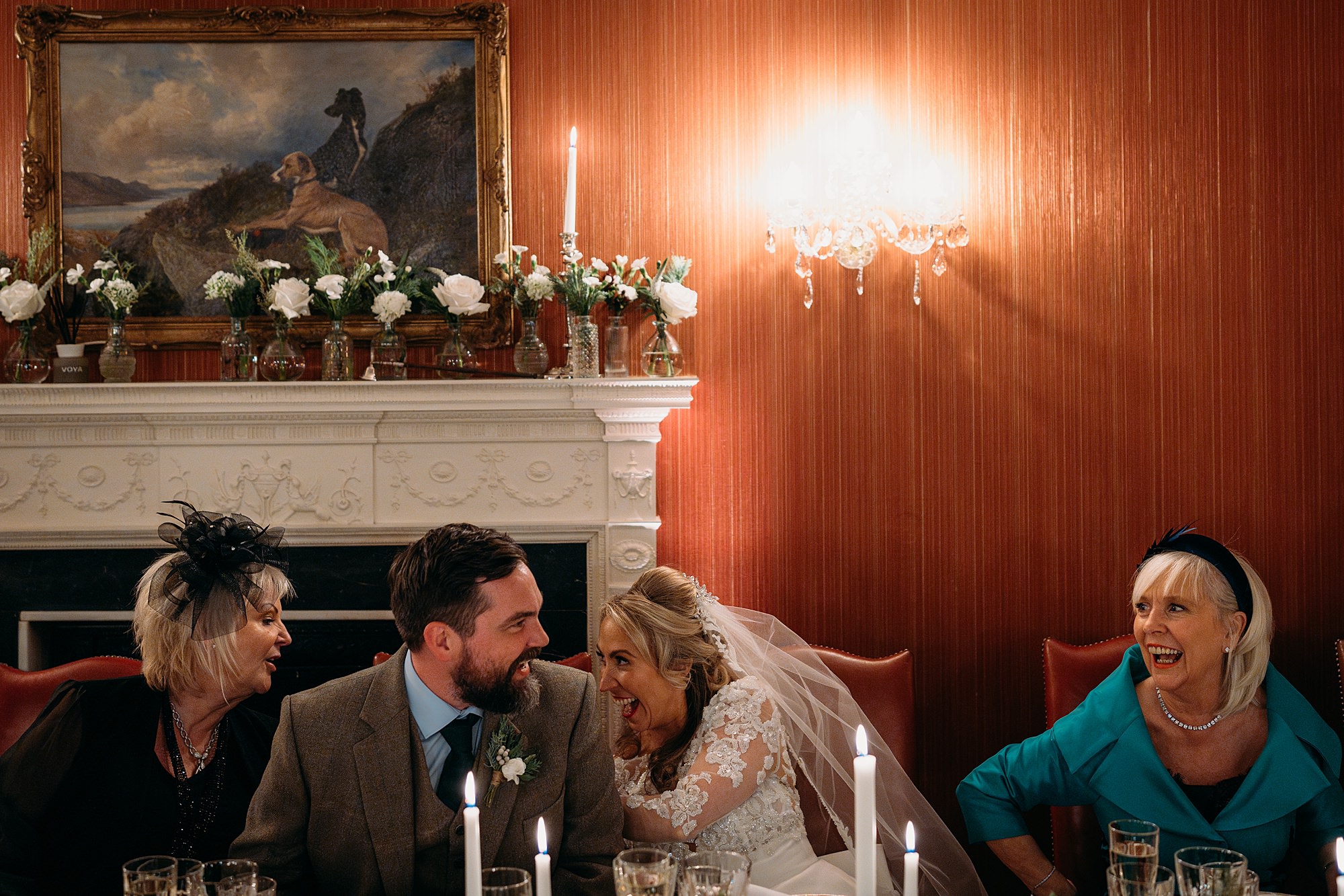 Bride and groom laugh with their mums. They all sit in a row during speeches. Archerfield House relaxed wedding photography