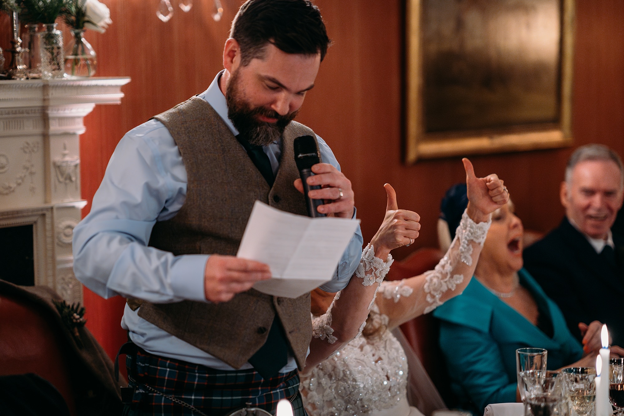 bride gives thumbs up during grooms speech. relaxed wedding photography at Archerfield House.