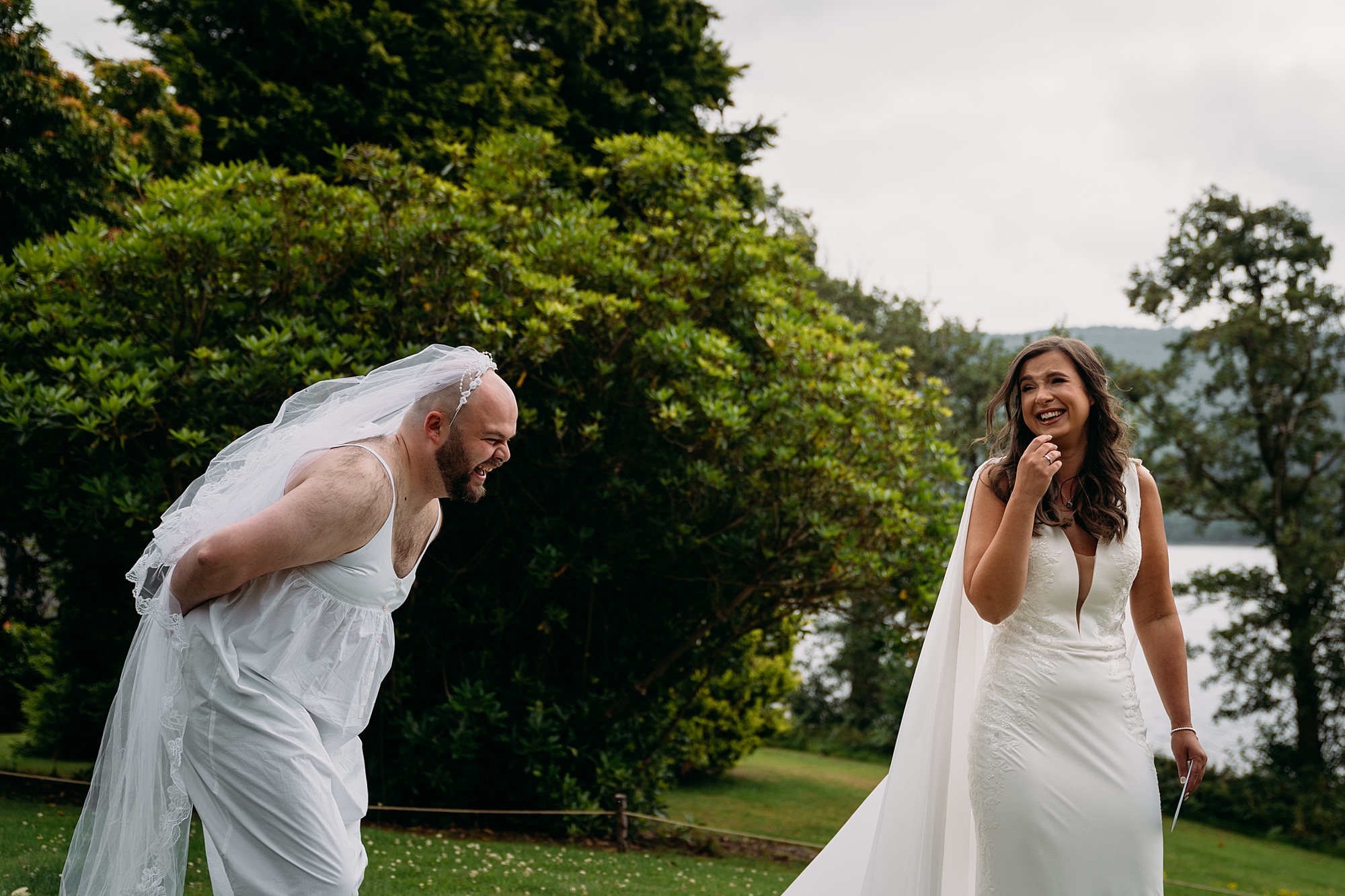Bride laughs as she is surprised by her male friend in a wedding dress, she was expecting her wife to be. relaxed wedding photography at Venachar Lochside.
