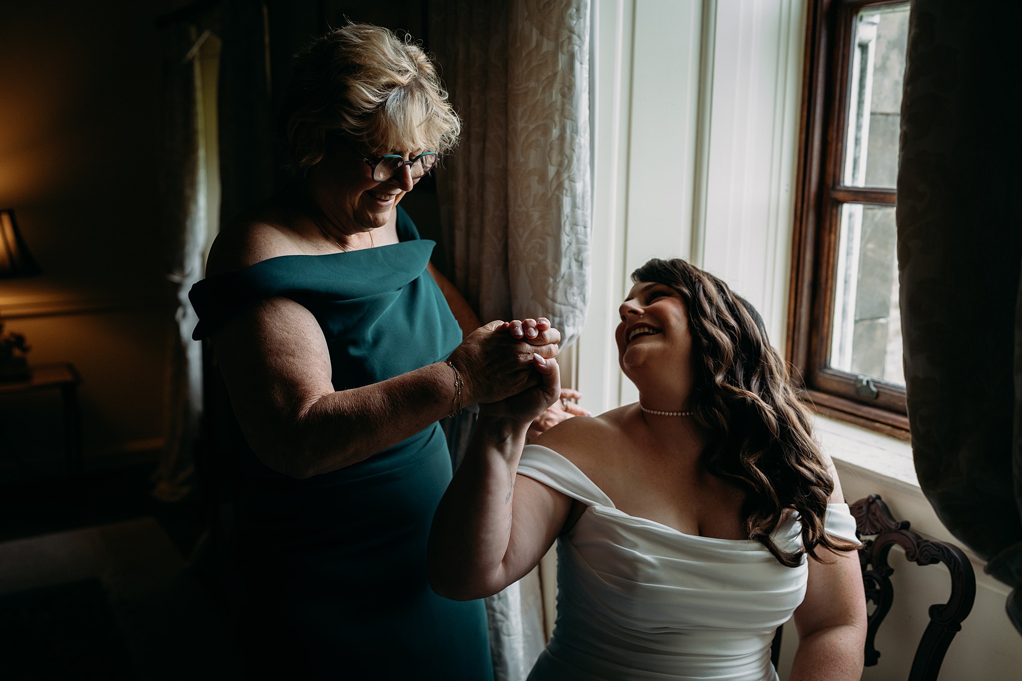 bride and Mum hold hands and laugh during relaxed wedding photography at Rowallan Castle.