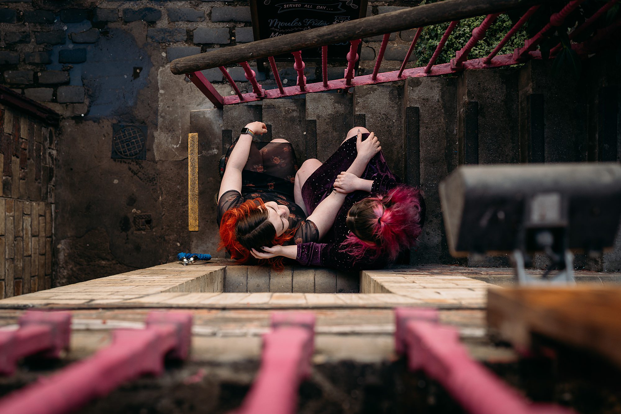Lesbian couple embrace in West End. Photograph is taken above from a flight of stairs. Relaxed wedding photography in Glasgow.