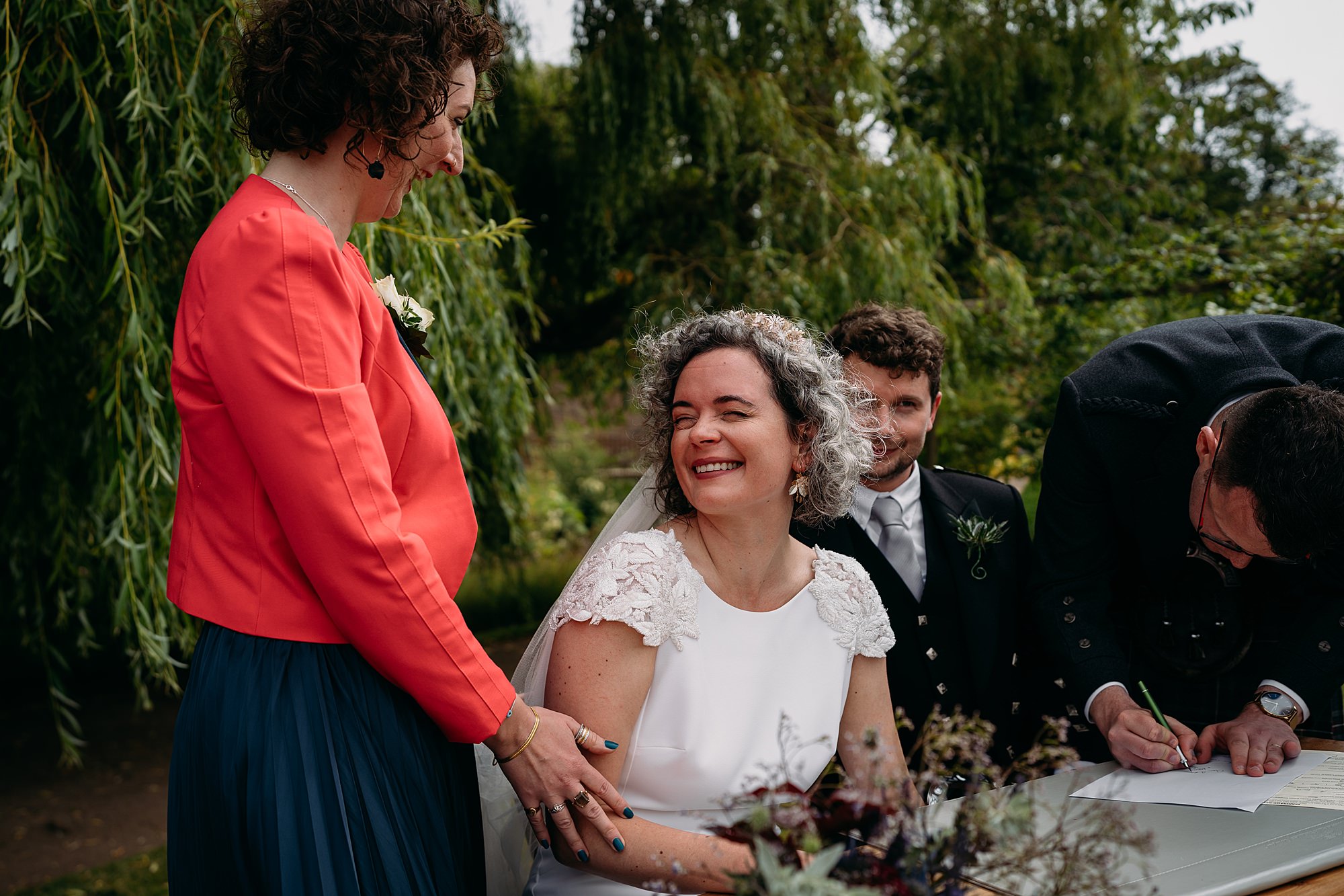 Best friend touches brides arm, bride smiles. Relaxed wedding photography at Cambo Estate. 
