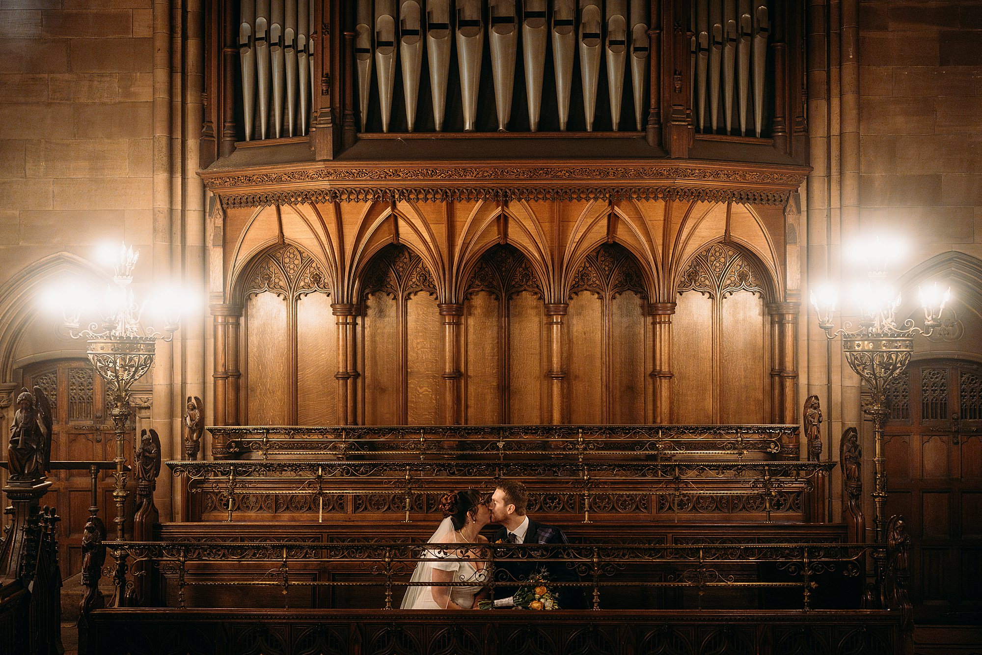 Bride and groom kiss in pews at Coats Paisley Twilight Wedding