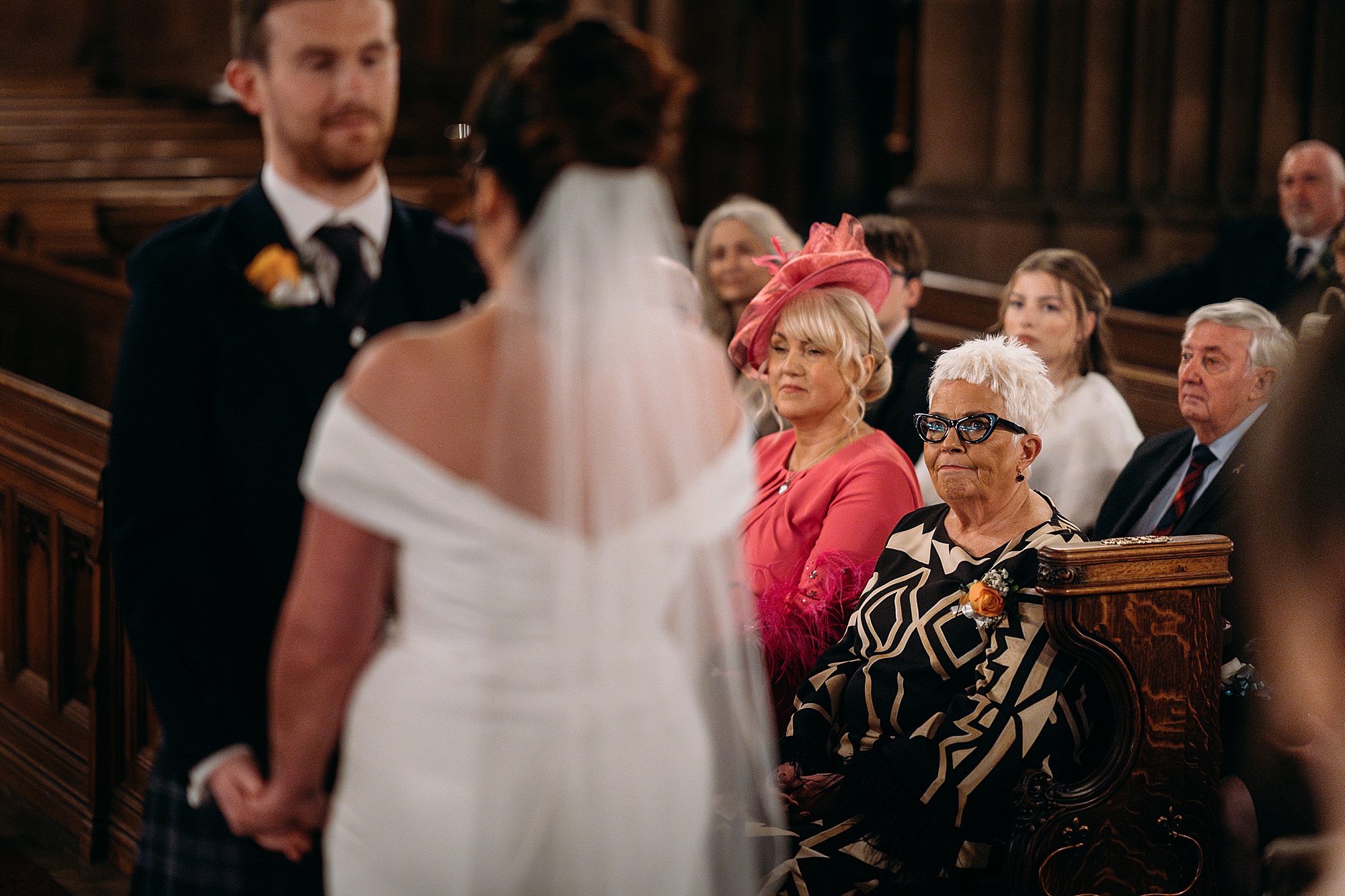 Brides mum looks lovingly at bride and groom during Coats Paisley Twilight Wedding ceremony