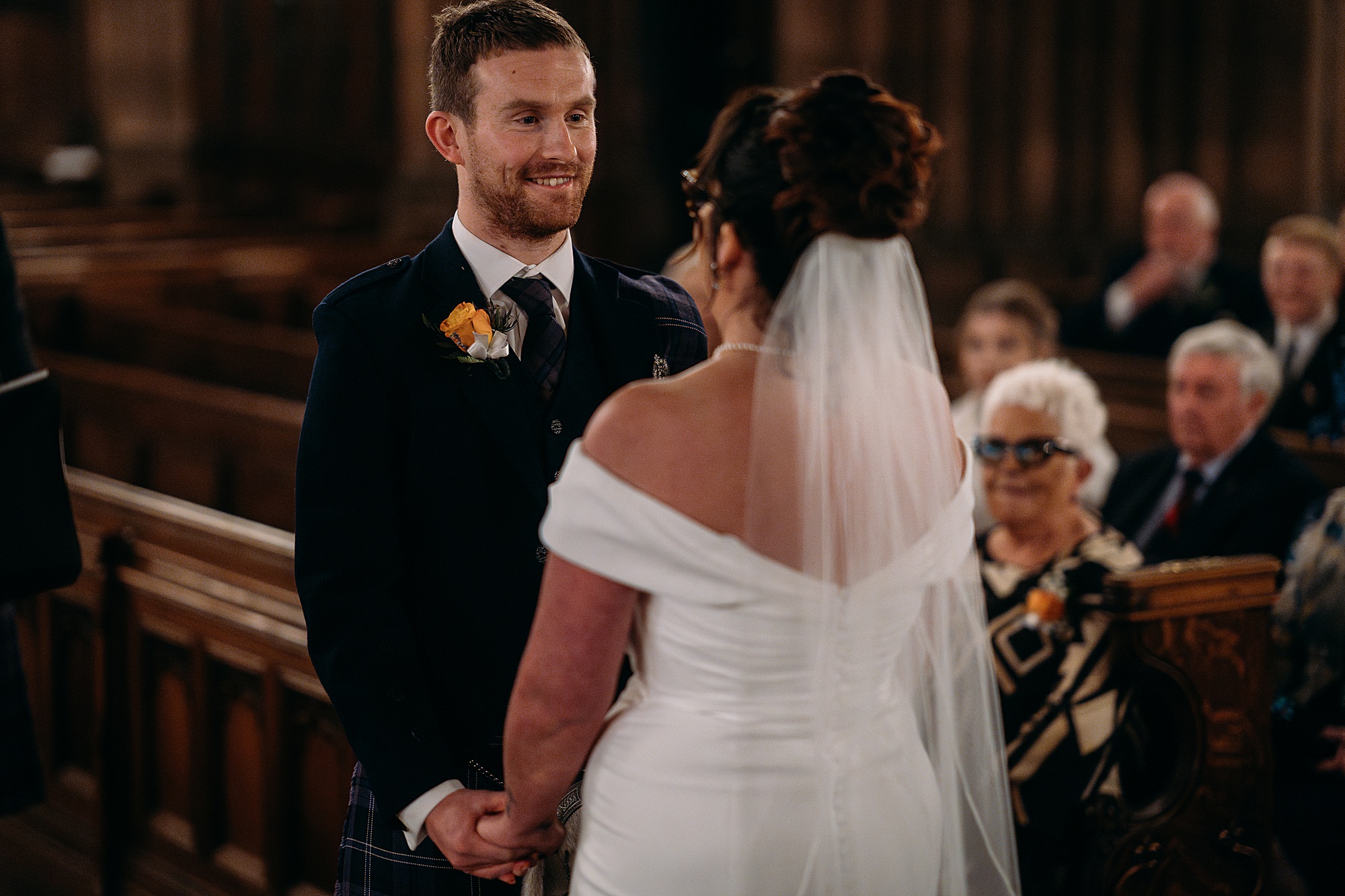 Groom smiles at bride during Coats Paisley Twilight Wedding ceremony