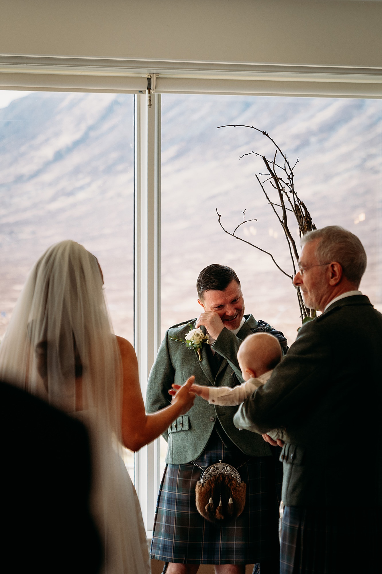 Groom cries seeing bride walk down aisle with son. Brides dad looks on at daughter with love during Kingshouse Hotel Glencoe wedding.